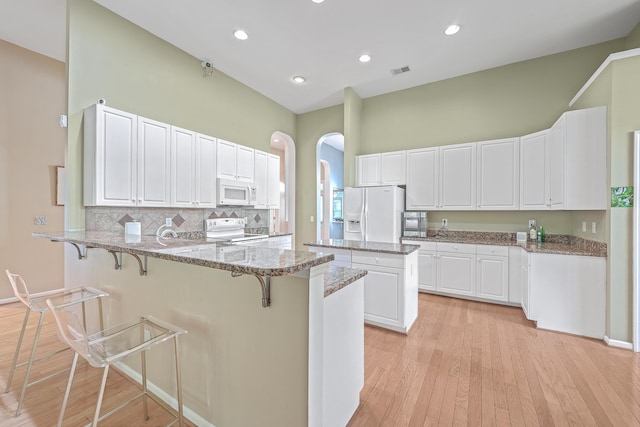 kitchen featuring dark stone countertops, white cabinetry, white appliances, and light wood-type flooring