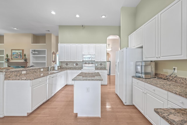 kitchen with white appliances, a center island, white cabinetry, and light hardwood / wood-style floors