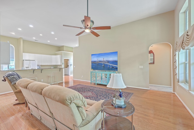 living room featuring a high ceiling, light hardwood / wood-style flooring, and ceiling fan