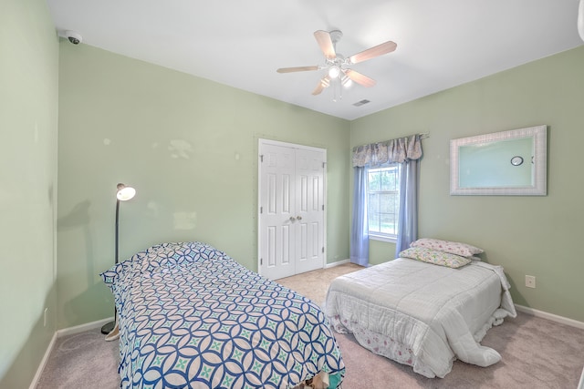 carpeted bedroom with ceiling fan and a closet