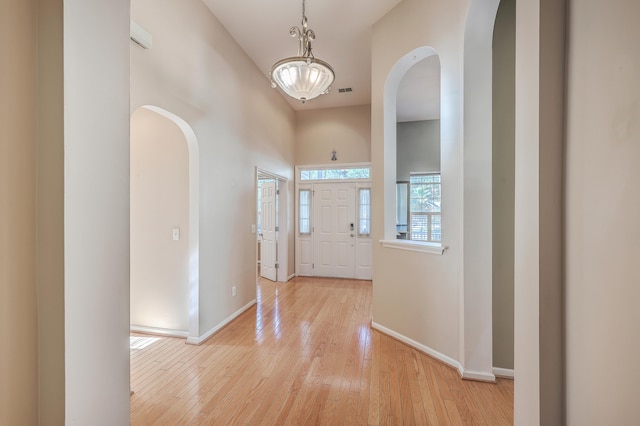 entrance foyer with a towering ceiling and light hardwood / wood-style floors