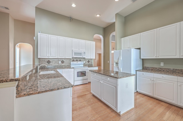 kitchen with a center island, white appliances, sink, light hardwood / wood-style flooring, and white cabinetry