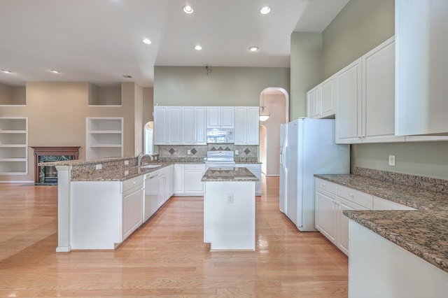 kitchen featuring white cabinets, white appliances, kitchen peninsula, and dark stone counters