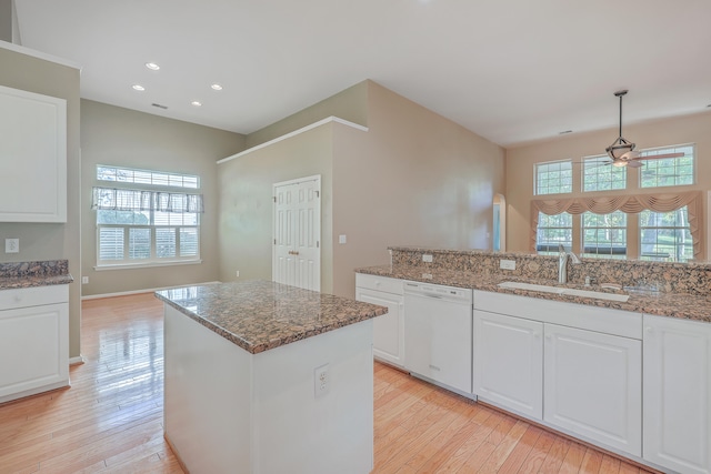 kitchen with dark stone counters, pendant lighting, light hardwood / wood-style flooring, dishwasher, and white cabinetry