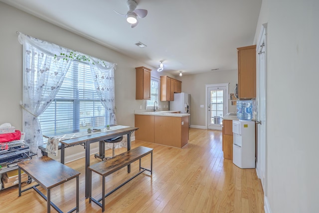 kitchen featuring light countertops, white refrigerator with ice dispenser, visible vents, and light wood-type flooring