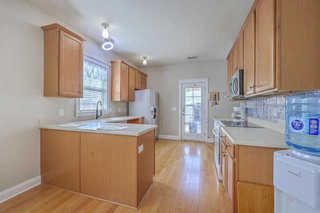 kitchen with a sink, white appliances, a peninsula, and light countertops