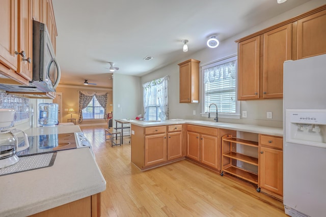 kitchen featuring light wood-style flooring, a sink, light countertops, white refrigerator with ice dispenser, and stainless steel microwave