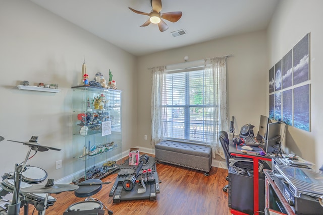 interior space with ceiling fan, visible vents, baseboards, and wood finished floors