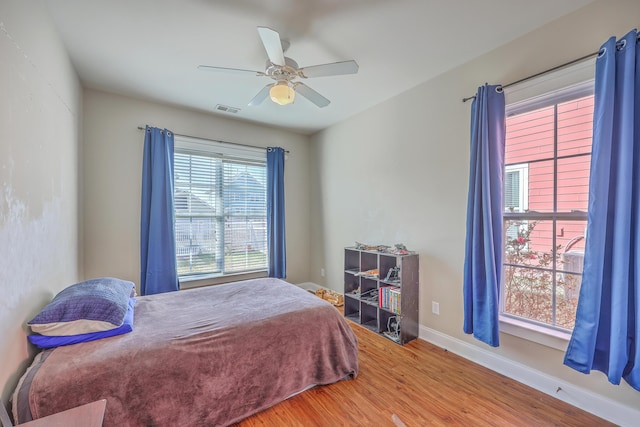 bedroom with visible vents, ceiling fan, baseboards, and wood finished floors