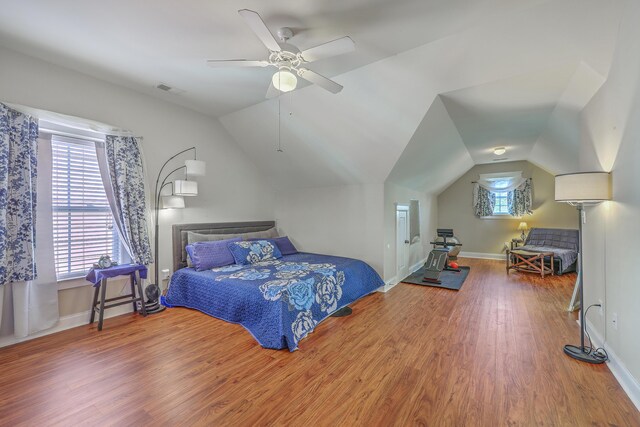 bedroom featuring a ceiling fan, wood finished floors, baseboards, visible vents, and vaulted ceiling