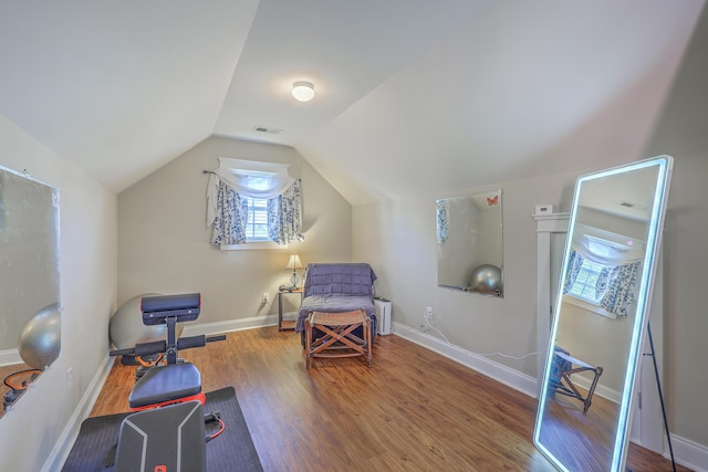 workout room with visible vents, baseboards, wood finished floors, and vaulted ceiling