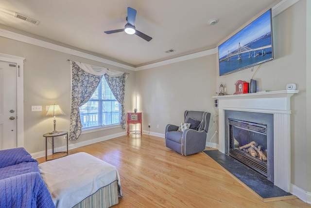 interior space featuring visible vents, crown molding, a glass covered fireplace, and wood finished floors