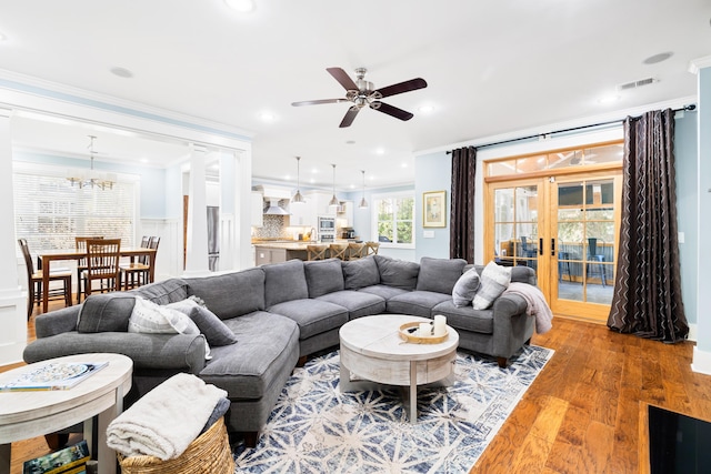 living area featuring french doors, crown molding, recessed lighting, visible vents, and wood finished floors