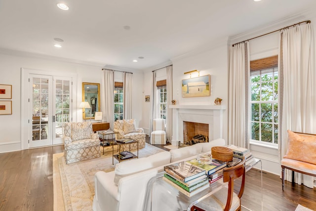 living room with a high end fireplace, wood-type flooring, ornamental molding, and a wealth of natural light