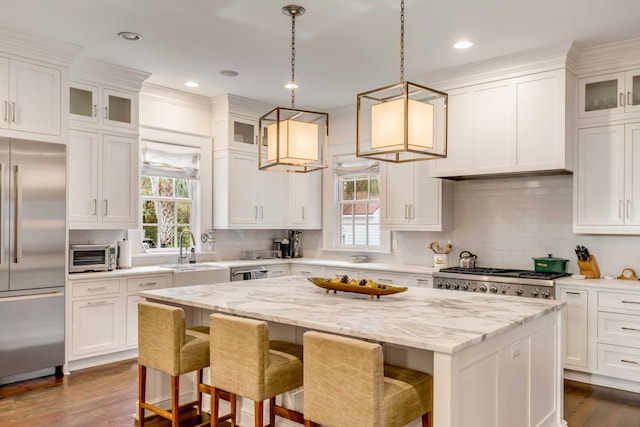 kitchen with pendant lighting, a center island, backsplash, white cabinets, and stainless steel appliances