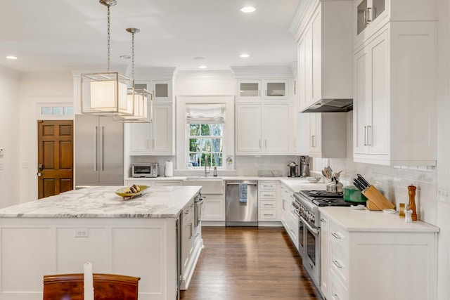 kitchen featuring premium appliances, dark hardwood / wood-style flooring, decorative light fixtures, white cabinets, and custom exhaust hood