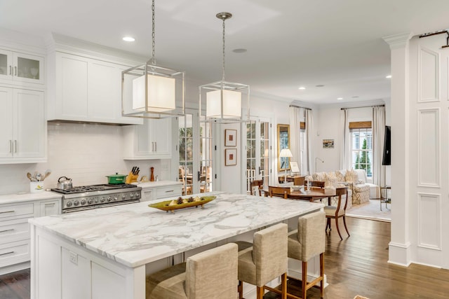 kitchen with white cabinets, dark hardwood / wood-style floors, a kitchen island, and high end stainless steel range oven