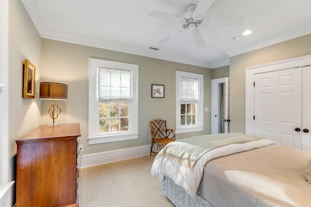 bedroom with ceiling fan, light colored carpet, crown molding, and a closet