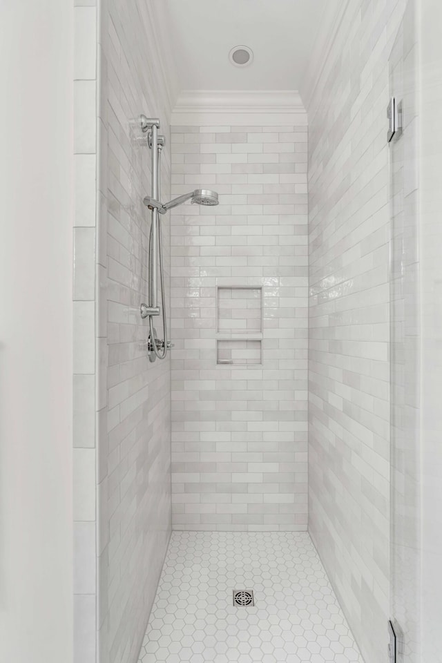 bathroom with tiled shower and crown molding