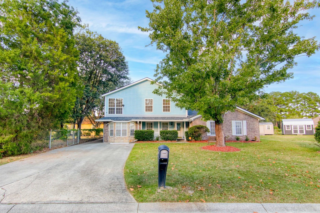 view of front of home featuring a storage unit and a front yard