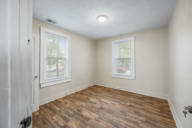 empty room with a textured ceiling and dark hardwood / wood-style flooring