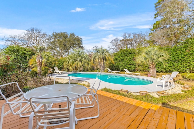 outdoor pool with outdoor dining area, a deck, and a diving board