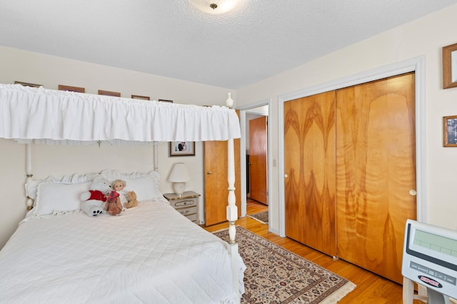 bedroom featuring light wood-type flooring, heating unit, a closet, and a textured ceiling