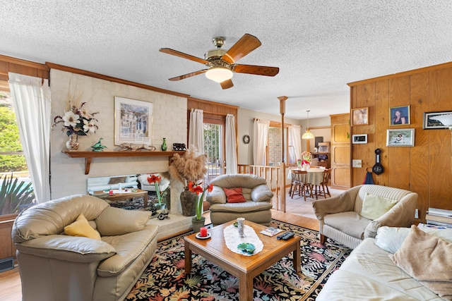 living room with ceiling fan, wooden walls, visible vents, and a textured ceiling