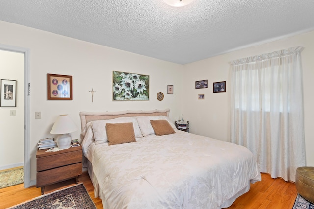 bedroom with a textured ceiling and light wood-type flooring