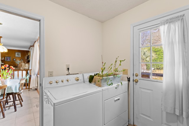 clothes washing area with laundry area, independent washer and dryer, a textured ceiling, and light tile patterned floors