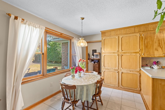 dining space with light tile patterned floors, baseboards, and a textured ceiling