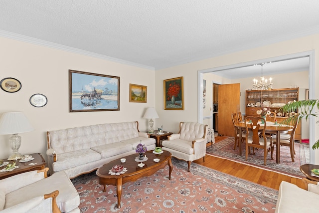 living room with a textured ceiling, a chandelier, wood finished floors, and ornamental molding