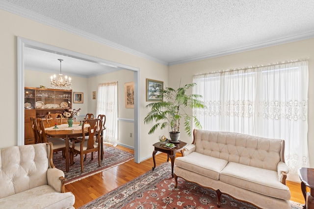 living area with a chandelier, plenty of natural light, wood finished floors, and crown molding