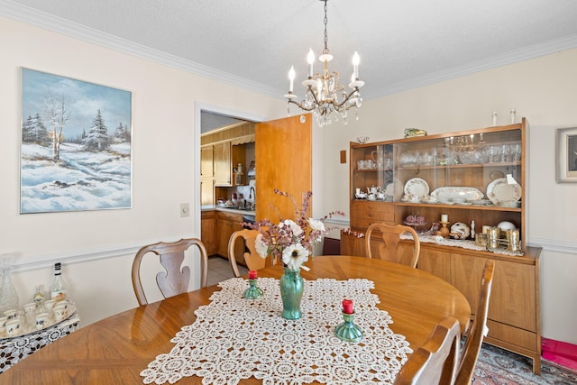 dining room featuring a notable chandelier, a textured ceiling, and crown molding