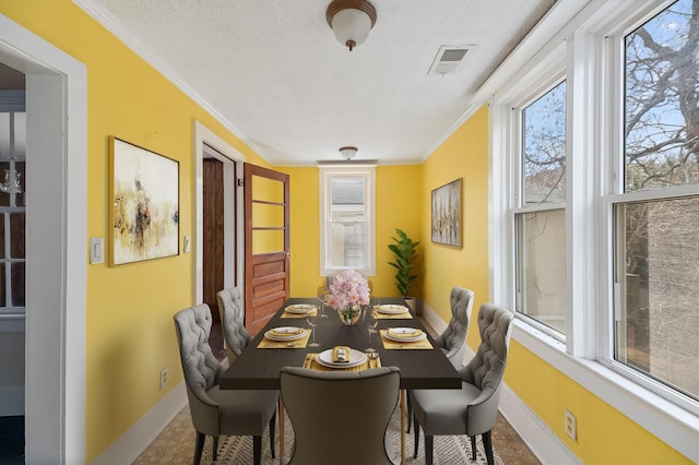 dining room with ornamental molding, visible vents, a textured ceiling, and baseboards