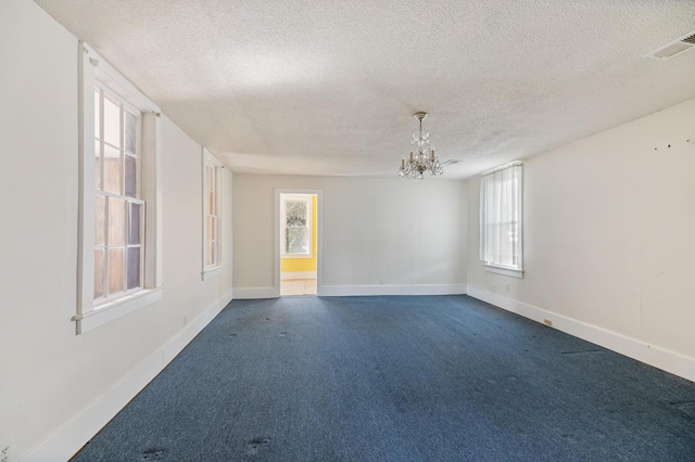 unfurnished room featuring baseboards, visible vents, dark colored carpet, and a wealth of natural light