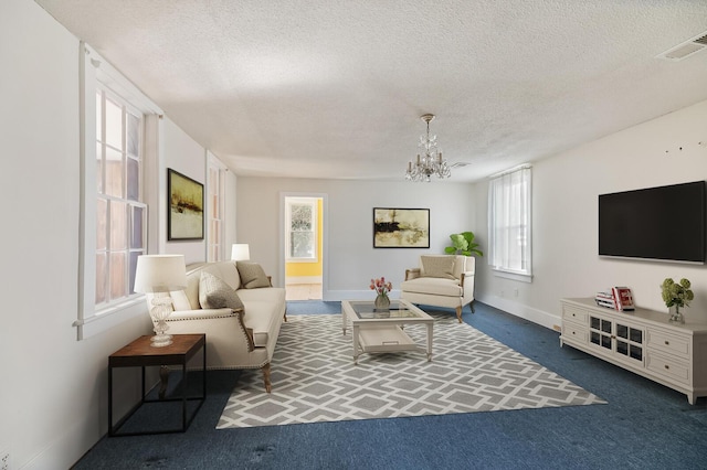 carpeted living room with a textured ceiling, a chandelier, visible vents, and baseboards