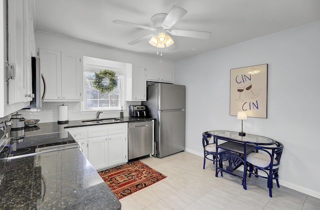 kitchen with a sink, baseboards, white cabinets, appliances with stainless steel finishes, and decorative backsplash