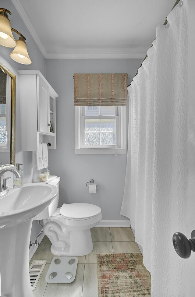 full bathroom featuring crown molding, toilet, a sink, baseboards, and tile patterned floors