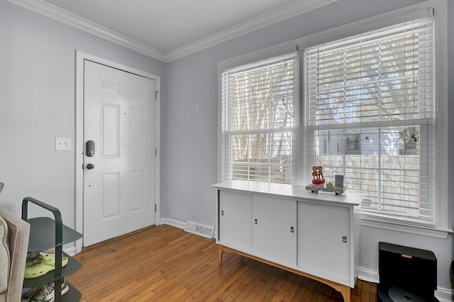 entrance foyer with hardwood / wood-style floors, ornamental molding, visible vents, and baseboards