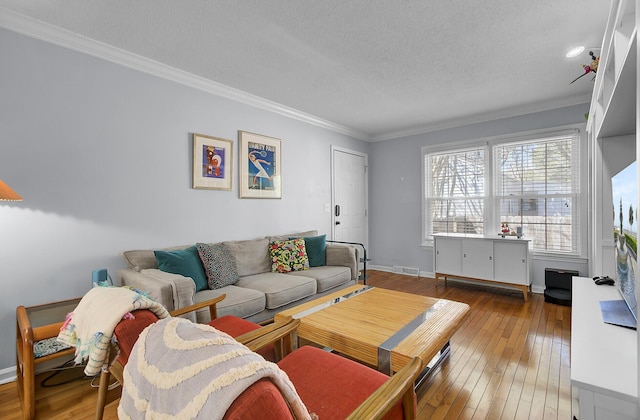 living area featuring crown molding, wood-type flooring, visible vents, a textured ceiling, and baseboards