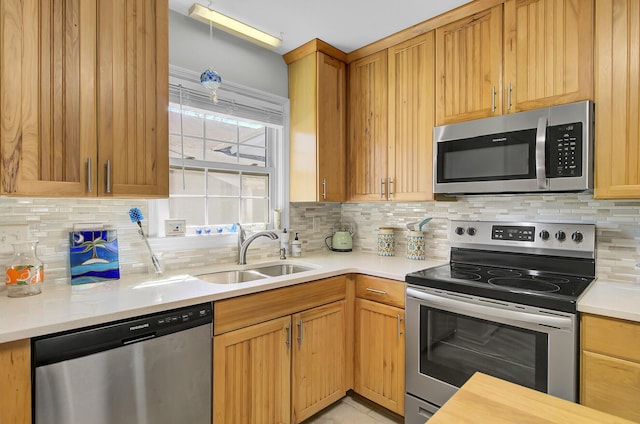 kitchen featuring light countertops, appliances with stainless steel finishes, a sink, and tasteful backsplash