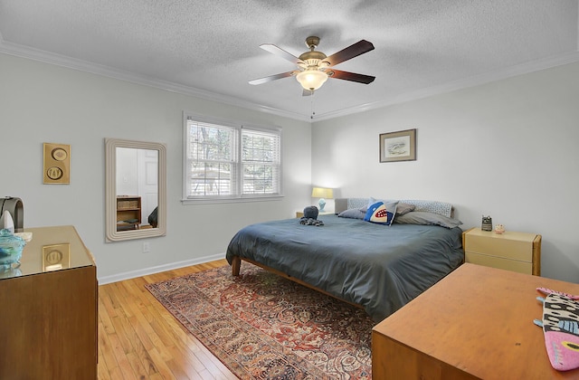 bedroom featuring a textured ceiling, ceiling fan, baseboards, light wood-type flooring, and crown molding