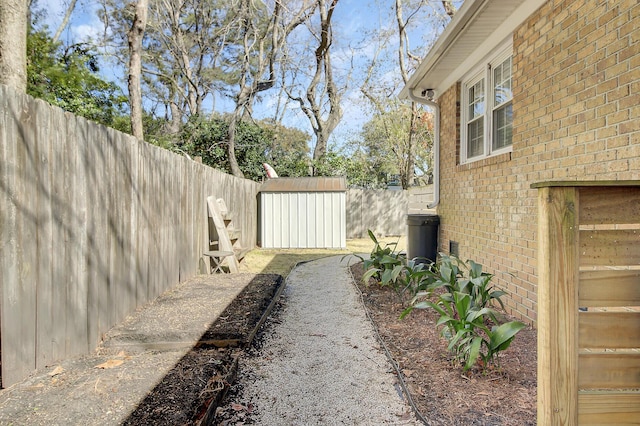 view of yard featuring a fenced backyard, a storage unit, and an outbuilding