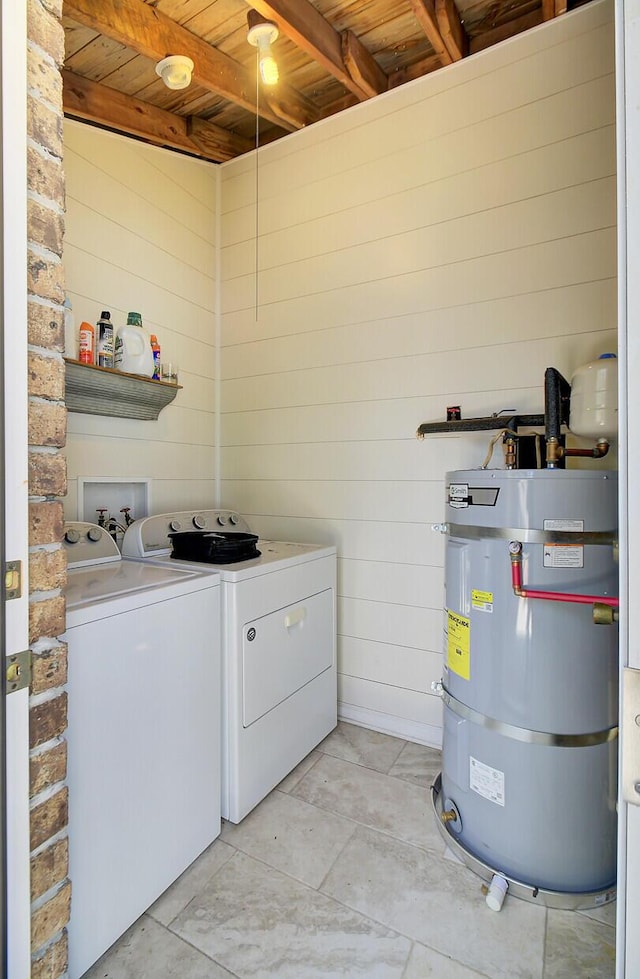 clothes washing area with wooden ceiling, wooden walls, laundry area, strapped water heater, and washer and clothes dryer