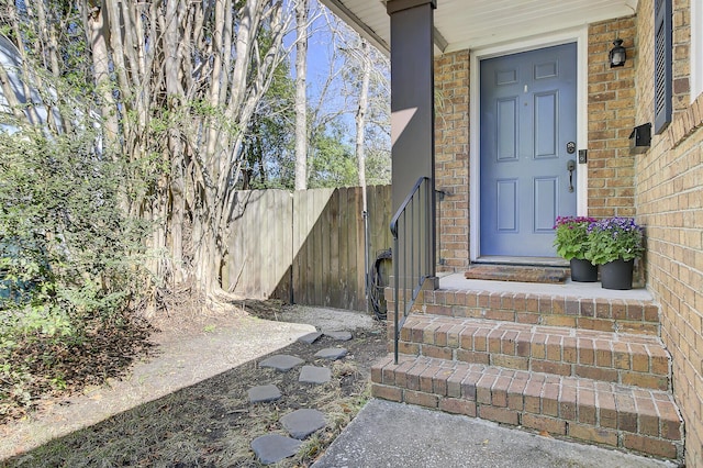 entrance to property featuring brick siding and fence