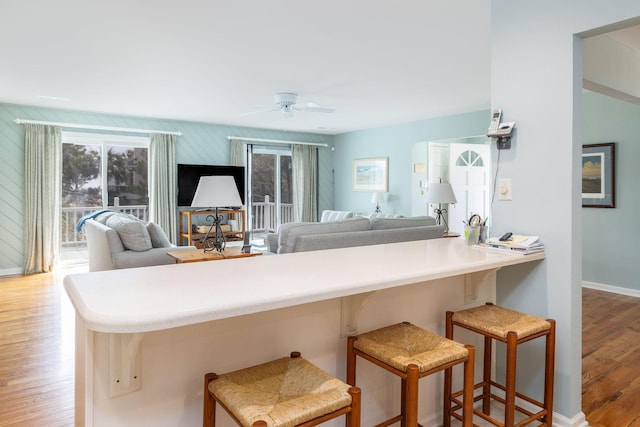 kitchen with plenty of natural light, wood finished floors, a ceiling fan, and a kitchen breakfast bar