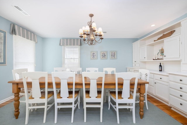 dining room featuring visible vents, a notable chandelier, and wood finished floors