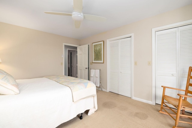 bedroom with baseboards, ceiling fan, light colored carpet, and multiple closets