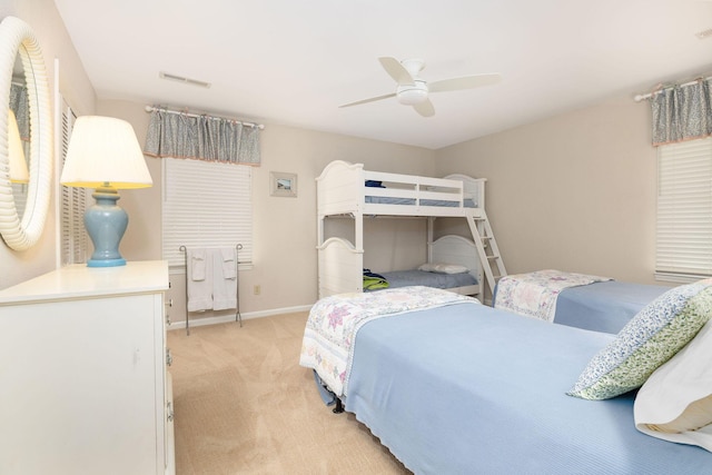 bedroom with light colored carpet, ceiling fan, visible vents, and baseboards